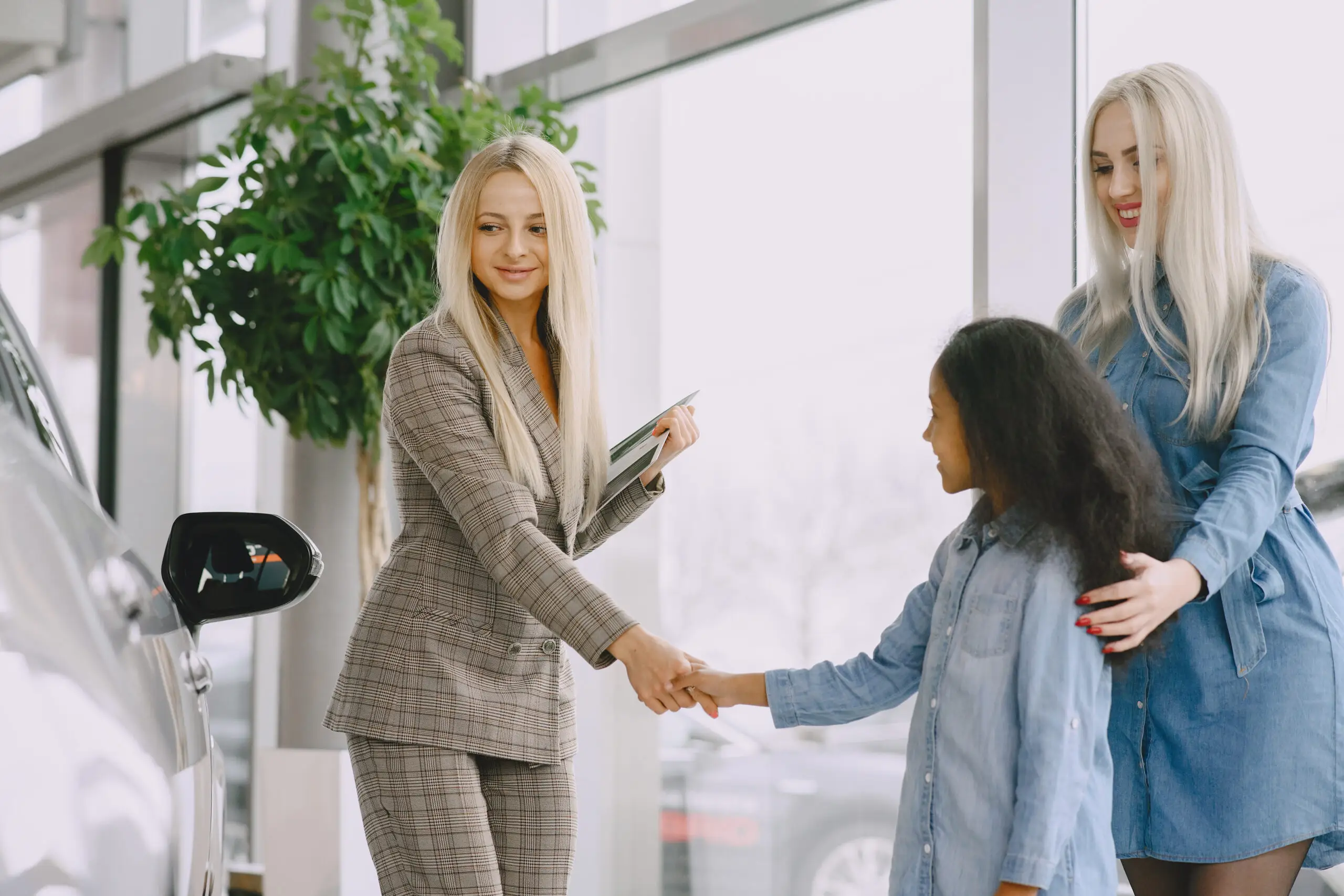 Caucasian mother with african daughter in a car salon