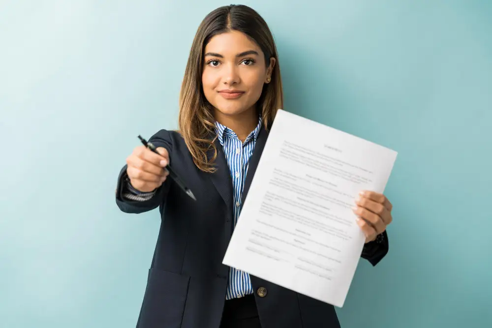 Business woman holding a document and offering a pen to sign.